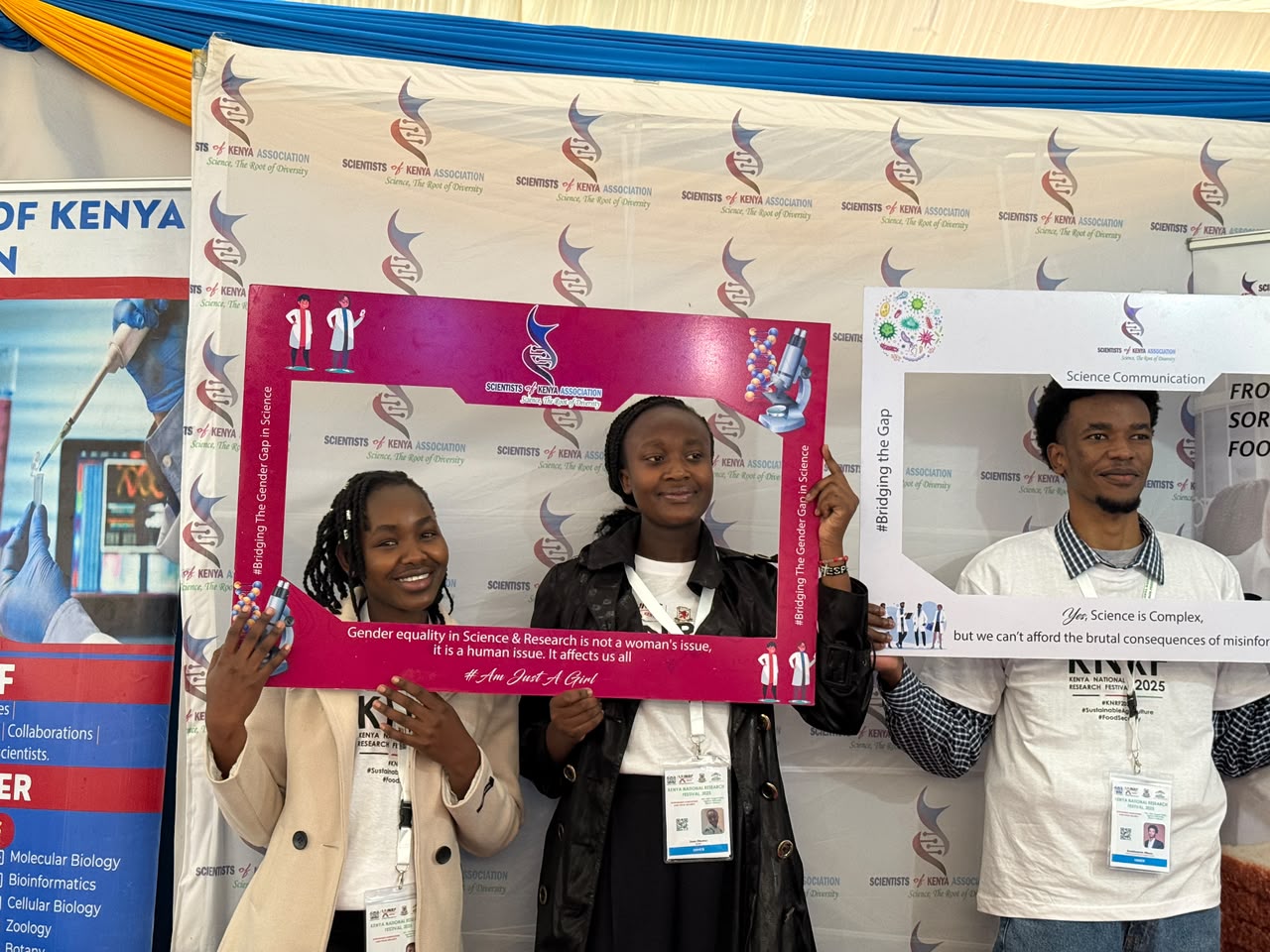 Young SCOKA members holding frames on gender equality in science and science communication at a research festival booth